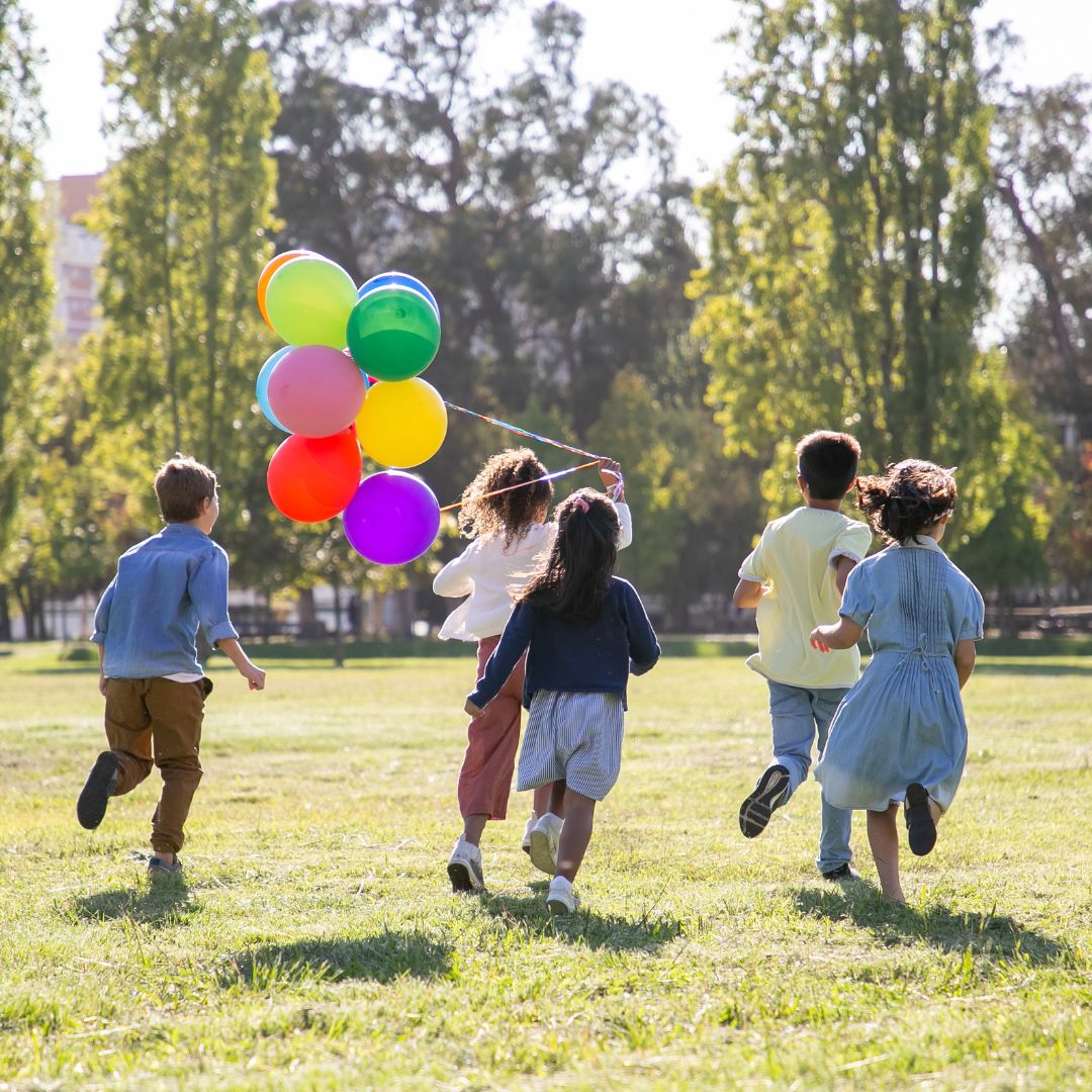Niños corriendo y jugando con globos